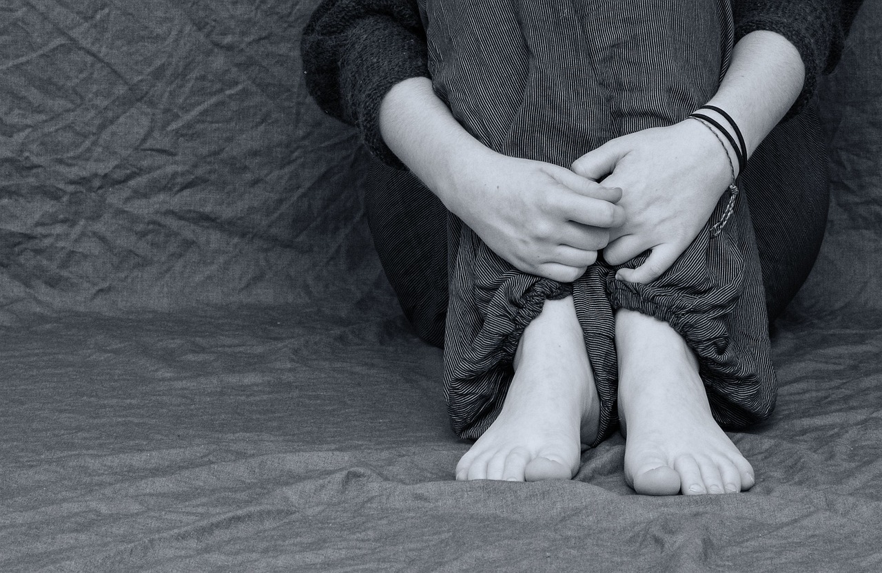 grieving girl sitting with hands folded